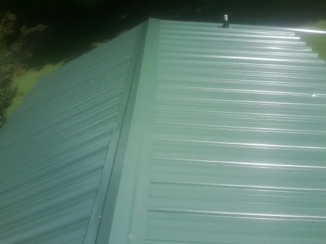New green metal panels meeting at the ridge of a roof — Flat Roof Repair work by our crew in Metaline
