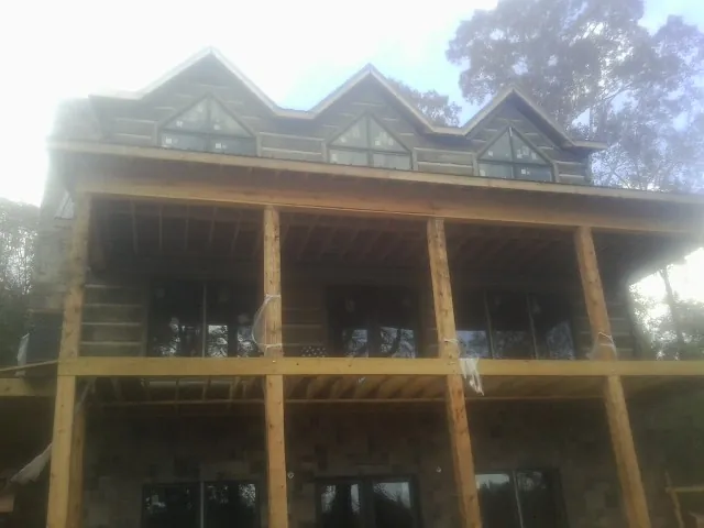 Dormers and porch framing on a large log home under construction — Roof Coating work by our crew in Metaline