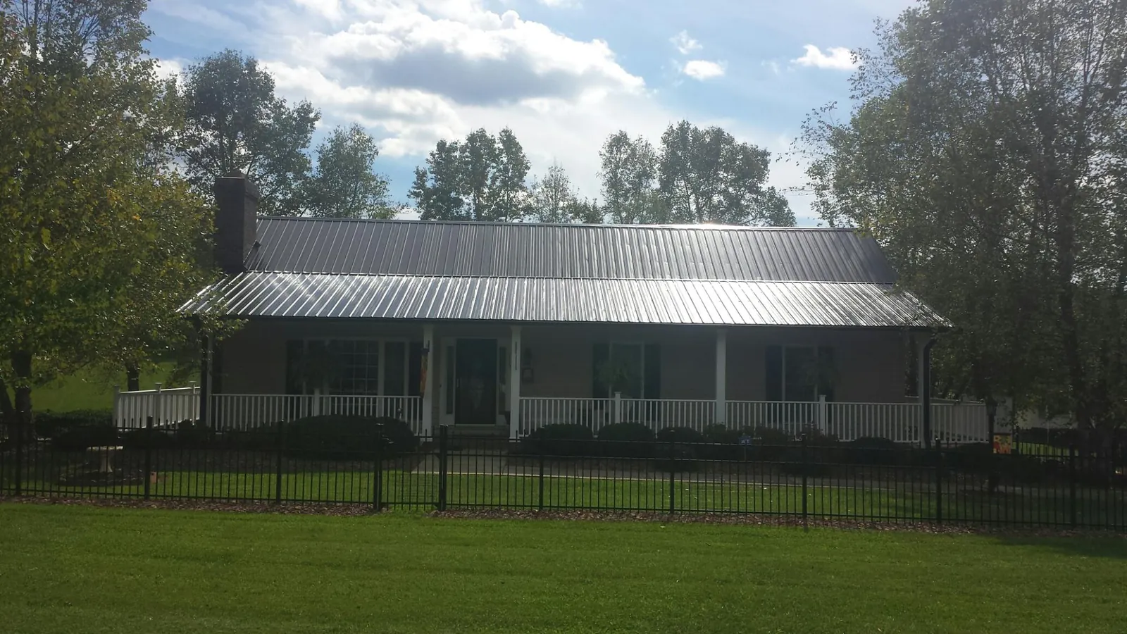 Gray metal roof on a brick ranch with a full width front porch — Gutter Guard Installation work by our crew in Metaline