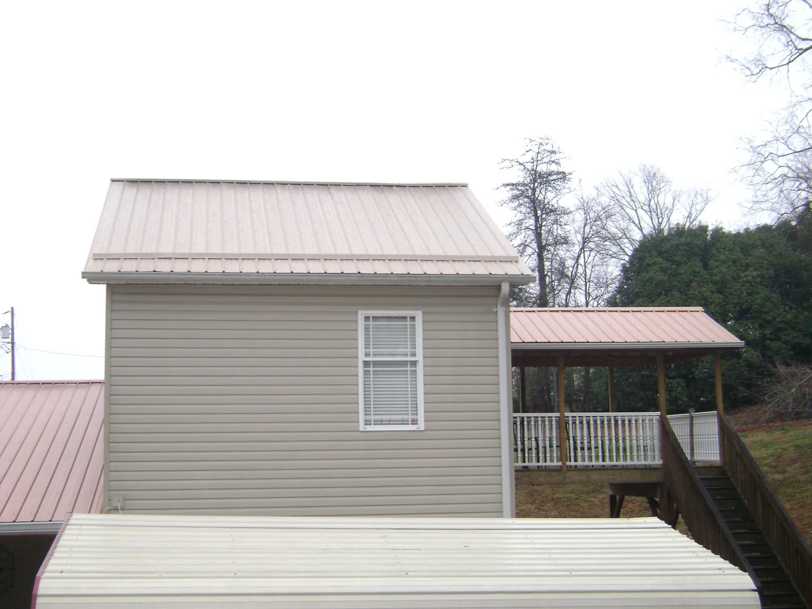 Tan metal roofs on a two story addition and attached porch, from a Roof Replacement job in Metaline