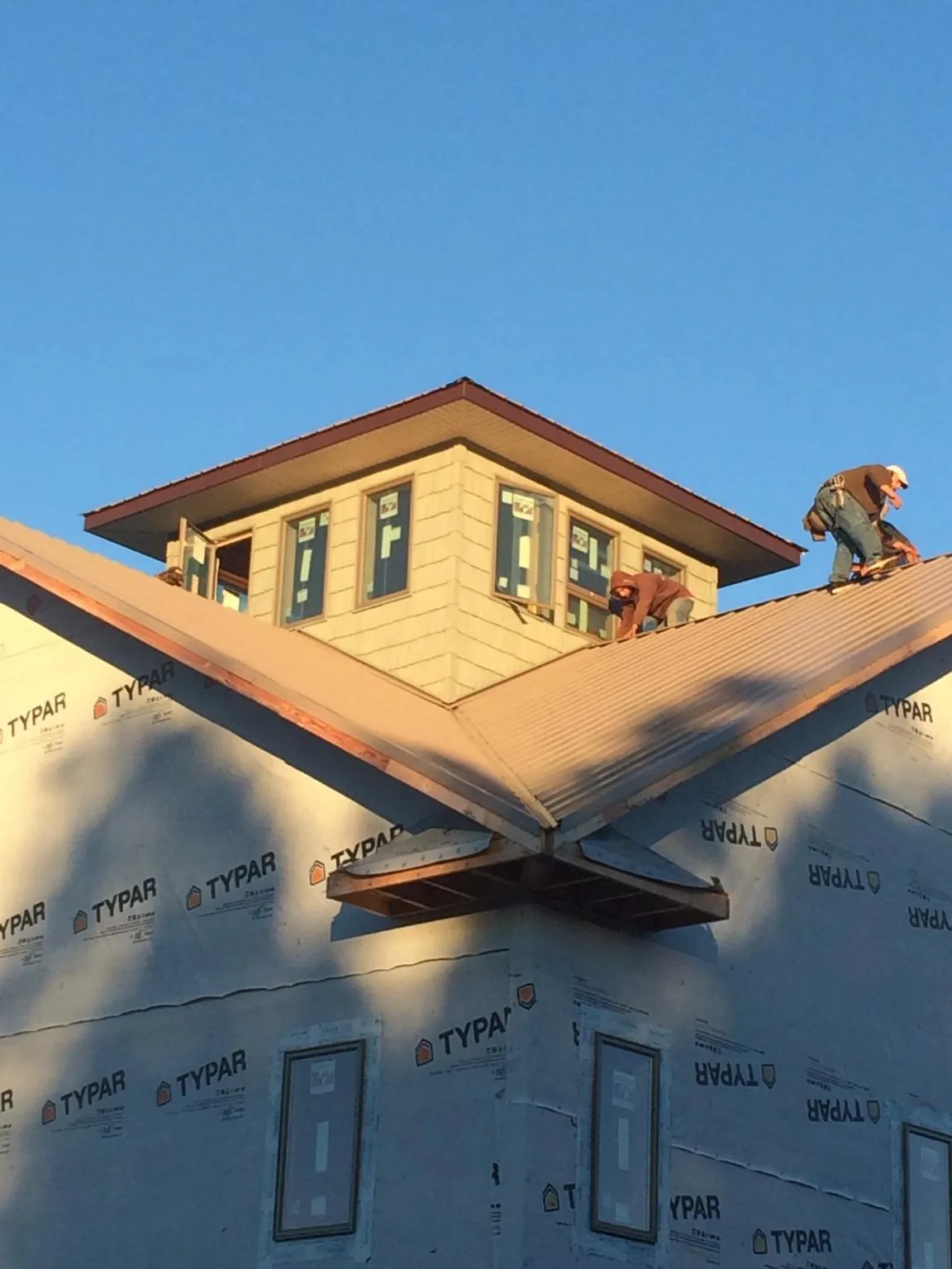Roofers working around a rooftop cupola on a new metal roof at sunset — Roof Waterproofing in Metaline by Roofing Brothers